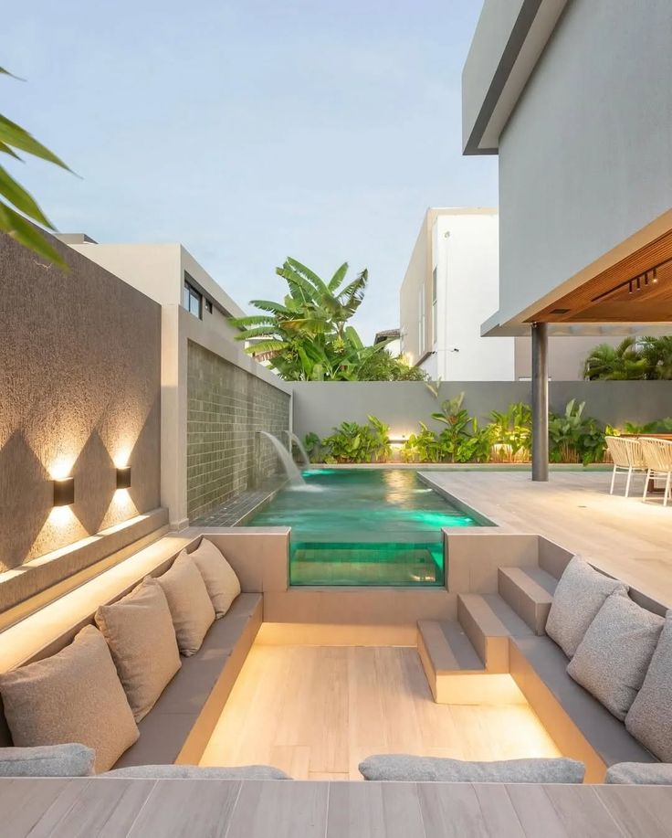 Sunken outdoor seating beside an illuminated swimming pool and tropical planting